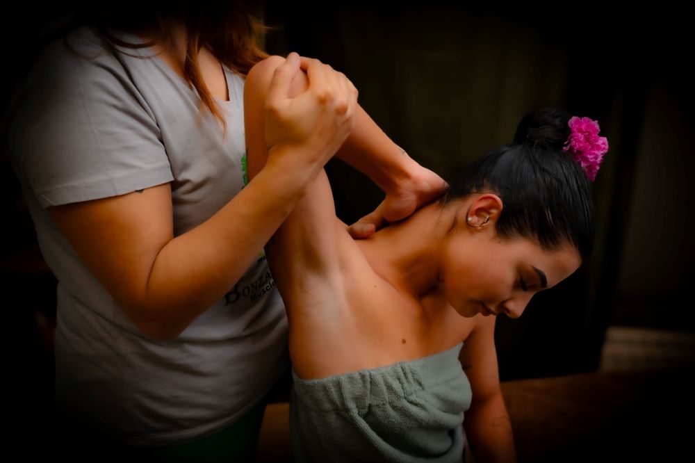 Massage therapeut van Bonzai24 in Amersfoort voert een diepe schouder- en nekstretch uit bij een vrouw tijdens een ontspannende wellness massage in een professionele massagesalon in Amersfoort.