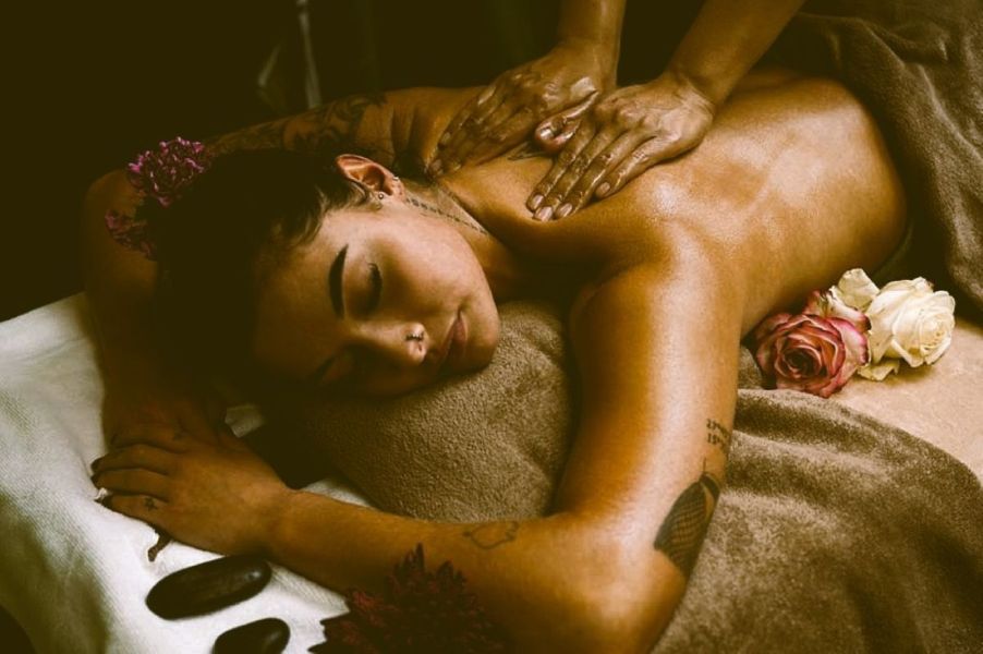 Vrouw ontvangt ontspannende massage in Amersfoort op massagetafel met warme olie, handdoeken en bloemen in wellnessruimte.